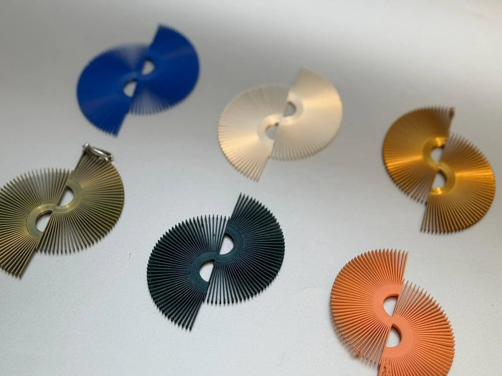 Assorted fan-shaped modern earrings in blue, gold, cream, green, and coral on white surface