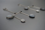 Modern geometric dangle earrings with black and gray circular accents on metal rods
