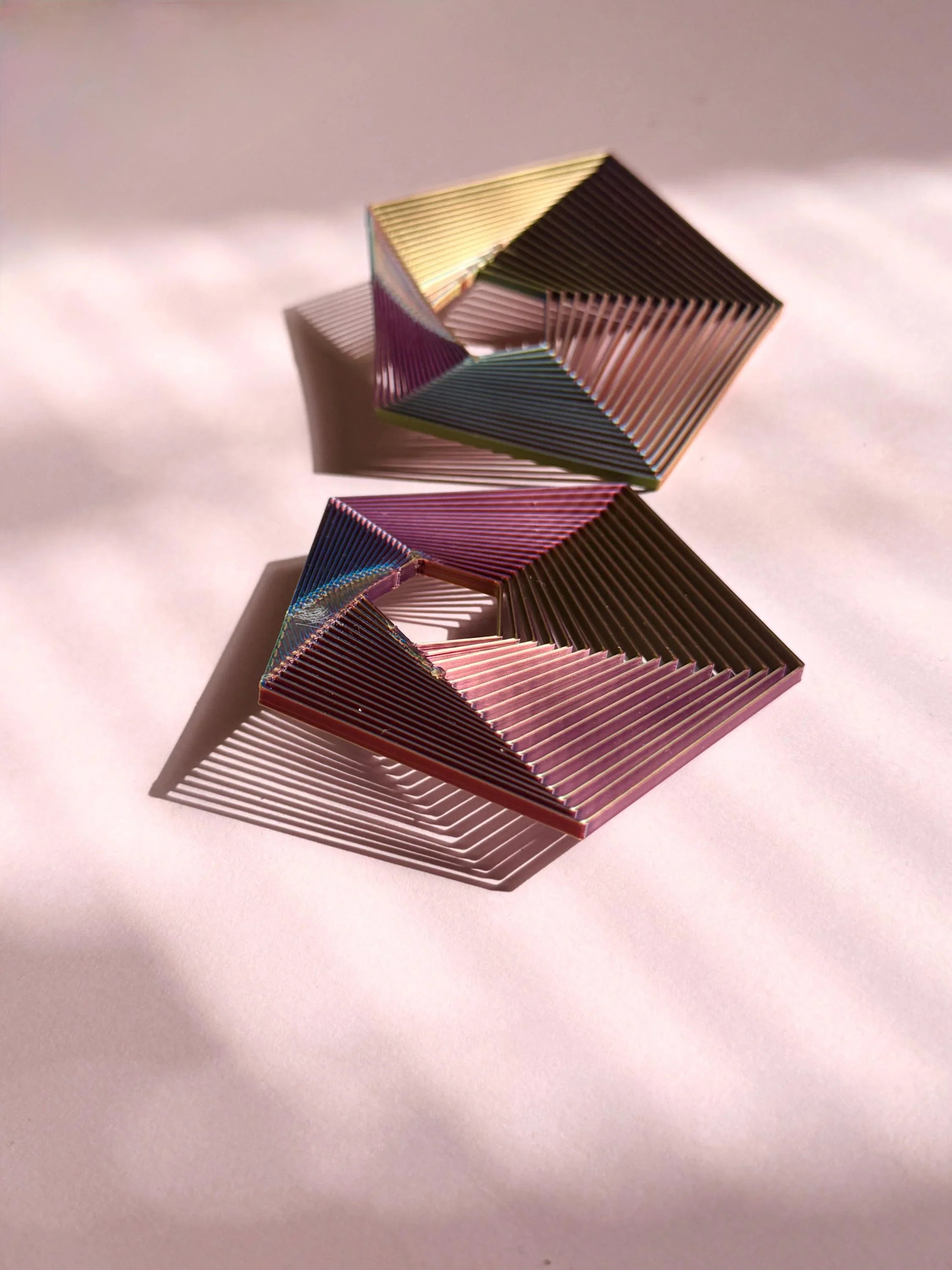 Geometric multicolor earrings with artistic lines casting shadows on a pastel background