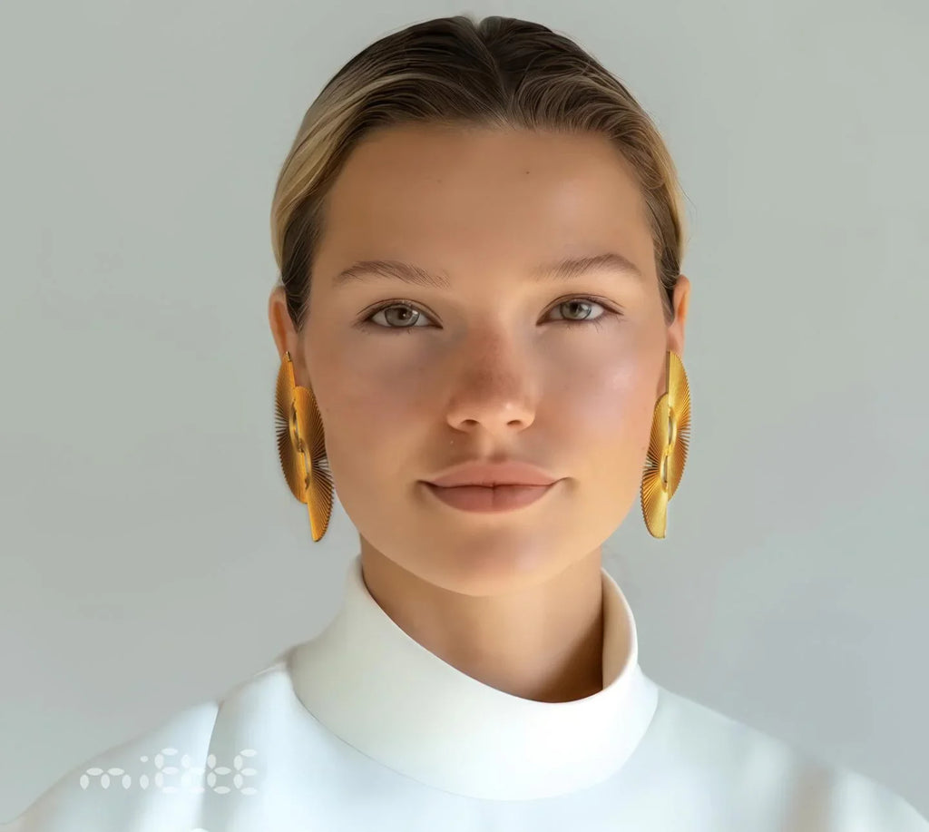 Woman wearing large artisanal gold statement earrings, minimalist background, modern jewelry