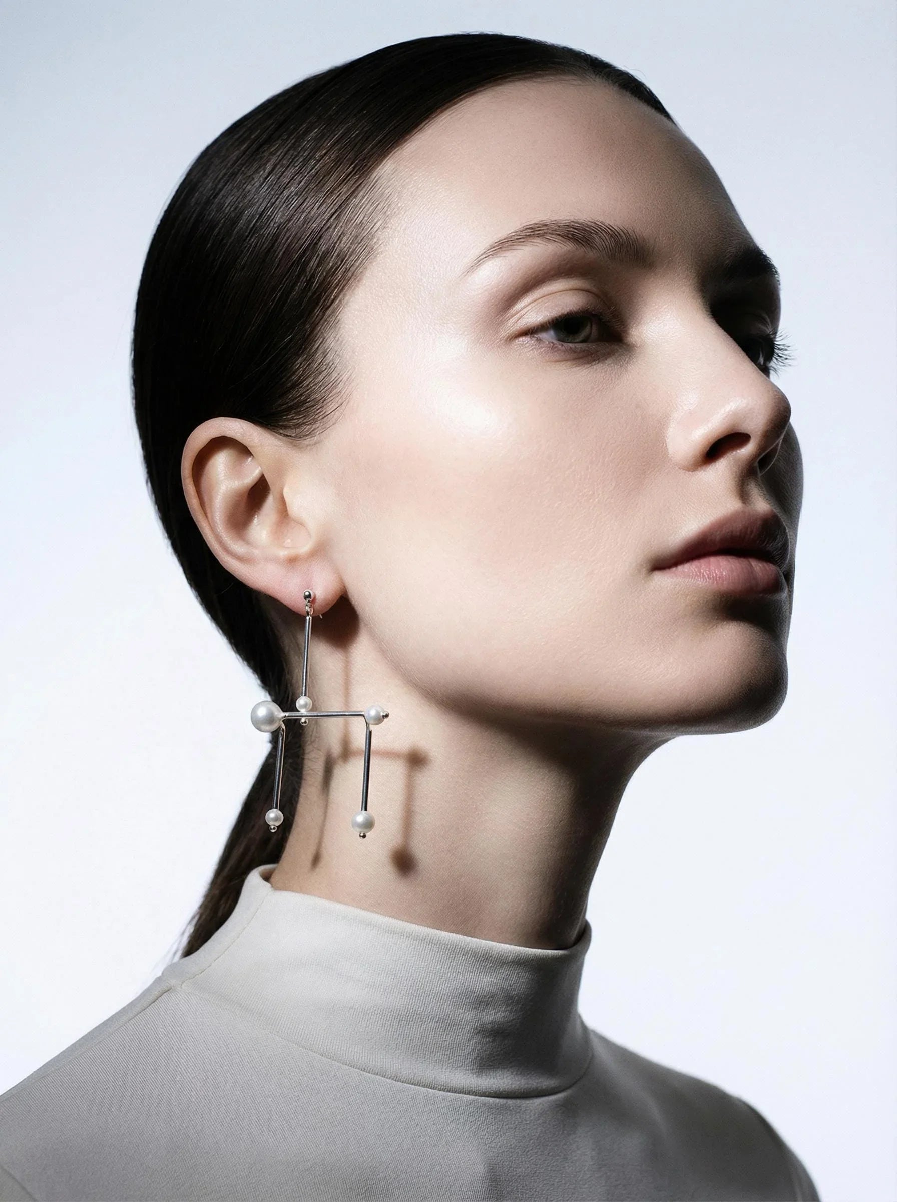 Woman wearing a modern geometric silver and pearl statement earring, minimalist style