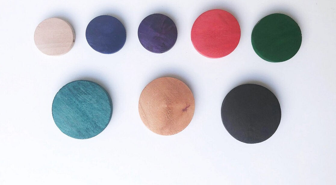 Assorted colorful round wooden discs on a white background, eco-friendly jewelry components.