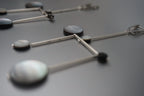 Geometric dangle earrings with silver bars and round shell-like accents on dark surface