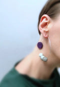 Modern statement earring with large purple and gray beads on woman’s ear