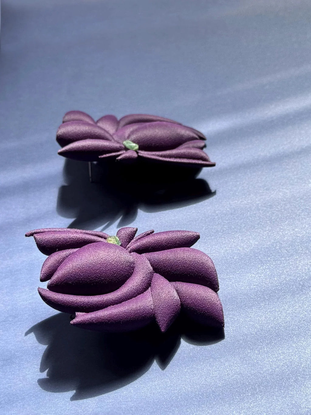 Pair of handcrafted purple flower earrings on a soft blue background